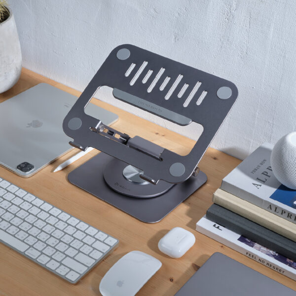 A metal laptop stand with USB hub from Eili Industrial on a wood desk with lots of stuff